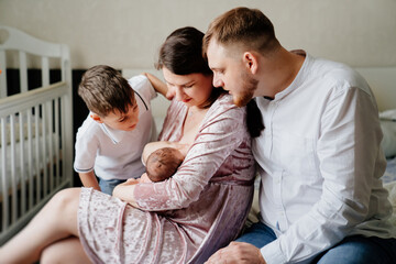 Happy family with toddler in bedroom. mom breastfeeds 