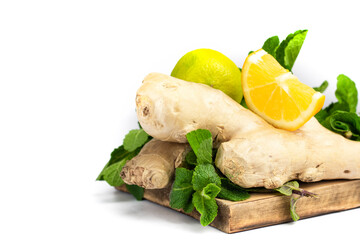 Ginger root, green fresh mint and lemons on wooden tray.