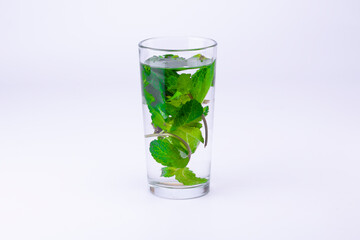 Glass with transparent alcohol liquid and mint leaves isolated on white background.