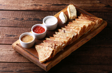 Russian and Ukrainian cuisine. Pancakes with sour cream, butter and red caviar on a wooden board on...