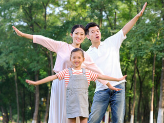 Naklejka na ściany i meble Happy family of three playing in the park