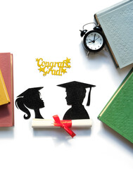 paper silhouettes of graduate students, Graduation diploma, alarm clock, pencils, books on white...