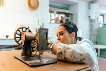 Small carpentry businessWoman working in her antique restoration workshop. person painting old sewing machine