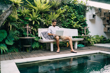 Focused man working on laptop on poolside