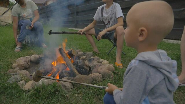 Happy kids roasting marshmallows on campfire in the evening
