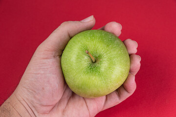 Green apple on the red background - man holding