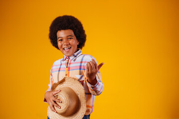 Portrait of a little boy afro wearing typical clothes for the Festa Junina,  Brazilian party called...