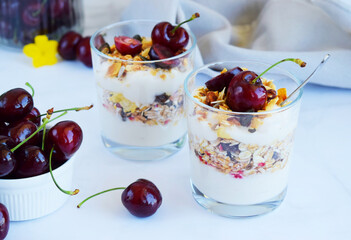 Close up dessert with cherries, Oat yogurt and granola in glass on marble background, Vegetarian...