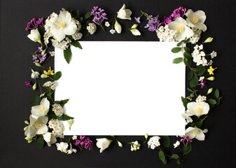 Floral frame made of different spring flowers on black background. Flowers flat lay. Space for text