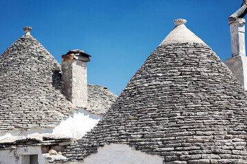 Fototapeta na wymiar Alberobello, Puglia, Brindisi, Italy - july 19, 2017: View of the Famous village with typical dry stone Trulli houses and conical roof. Trulli picturesque street in the old town. Cone-roofed houses