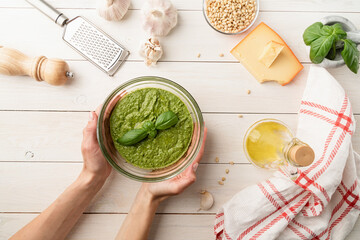 Preparing italian pesto sauce. Woman hands holding homemade pesto bowl