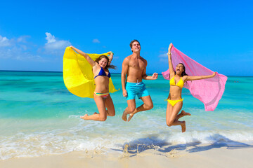 Three young beautiful people jumping for joy on the beach 