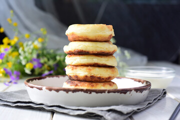 Sweet breakfast: hot cottage cheese pancakes on a white plate on a white background.