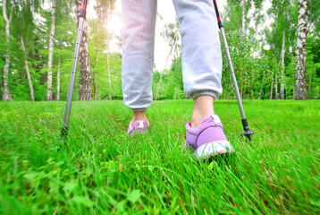 Nordic walking in nature. Girl with a walking sticks on the meadow. Hiking tourism background.