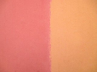 Fototapeta premium Background from the wall in pink and yellow. The texture is unevenly colored, rough, matte, a lot of smudges. The space is divided into two halves by color. 