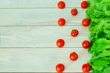 Naklejka na ściany i meble fresh lettuce and cherry tomatoes on a light wooden background. High quality photo