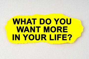 On a white background lies yellow paper with the inscription - WHAT DO YOU WANT MORE IN YOUR LIFE