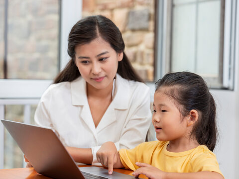 Young Happy mother and daughter use laptops