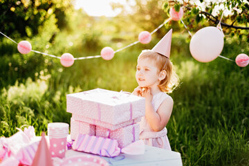 Happy birthday little girl with gift box in beautiful garden. child eat happy birthday rose cupcake. colorful pastel decoration outdoor. 4 years old kid celebrating enjoying party on summer day.