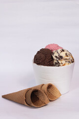 an isopor container with ice cream of different flavors and four cones, on a white background