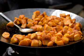 Chunks of fried potatoes in a large skillet during the street food festival.