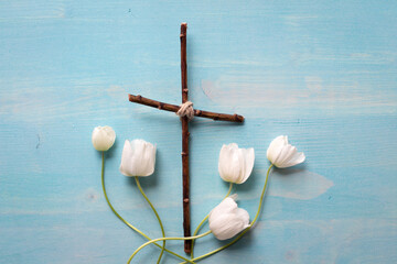 Christian cross with white anemone flowers on blue wood background with copy space