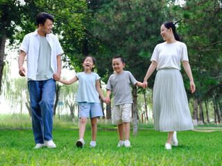 Naklejka na ściany i meble Happy family of four playing in the park