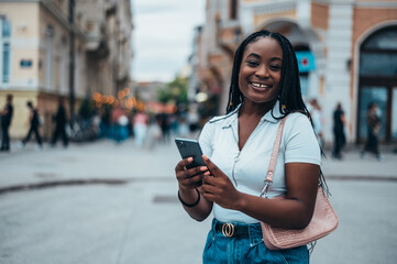 Cheerful african american woman using smartphone