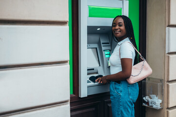 African american woman using credit card and withdrawing cash at the ATM