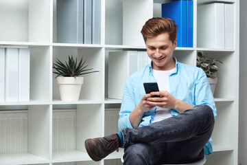 Young man navigate in his smartphone while standing in office