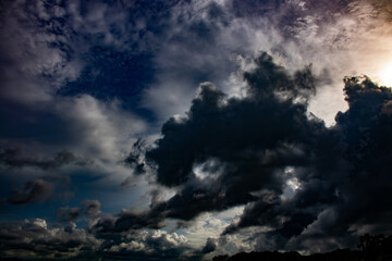 Thick black clouds in the sunny sky.