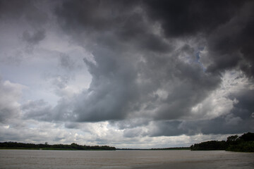 Cloudy skies. Thick black clouds on the chest of the river. The cloudy sky merged with the river.