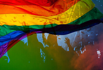 silhouette of a parade of gays and lesbians with a rainbow flag - symbol of love and tolerance - lgbt rights