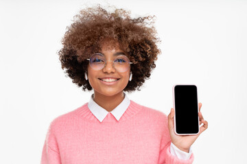 African female teen showing smart phone with blank screen with copy space, isolated on gray...