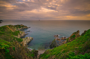 Summer sunset over the sea, high coastal cliffs
