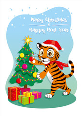 Naklejka premium Cartoon tiger in a hat decorates Christmas tree with toys for the New Year. Winter time. Happy New Year 2022 and Merry Christmas. Ideal for holiday card, postcard, poster, decoration