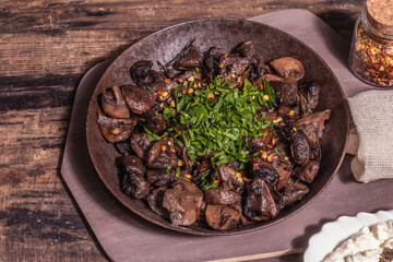 Fried royal champignons in an old cast-iron skillet with trendy hard light, dark shadow