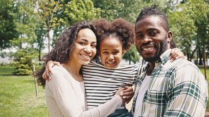 Close up portrait of laughing african couple and their little daughter in the park. Young happy parents, walking with their little adorable daughter