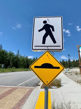 pedestrian crossing sign and speed bump sign and blue sky