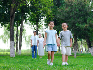 Naklejka na ściany i meble Happy family of four playing in the park