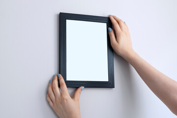 Hand Holding Blank white Photo Frame Hanging Wall for Design Mockup Template.