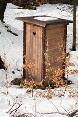 Wooden toilet outside with a heart in the doorway.