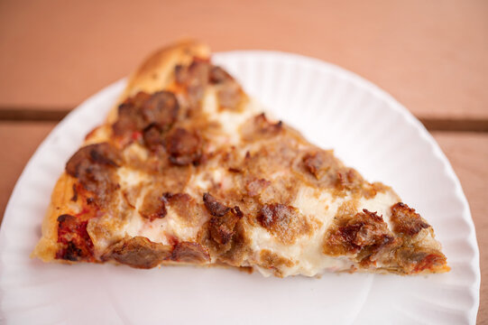 A Slice Of Sausage And Pepperoni Pizza On A Paper Plate.