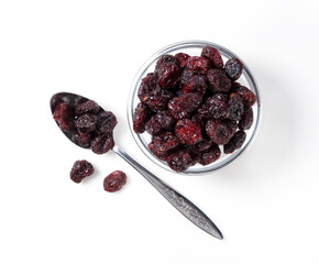 Dried cranberries in a glass bowl on a white background. A spoon next to it.