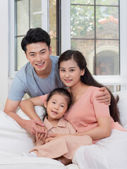 Obraz premium A happy family of three is sitting on the sofa in the living room