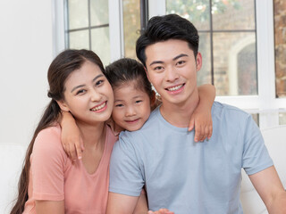 A happy family of three is sitting on the sofa in the living room