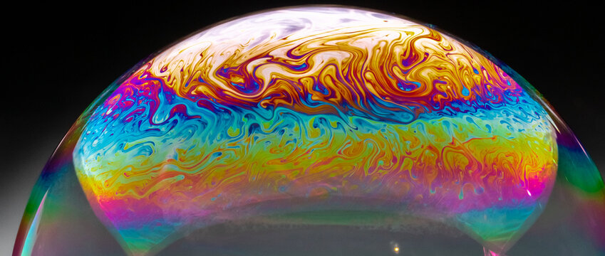 Vivid rainbow colours of a Macro soap bubbles creating psychedelic patterns under light dome