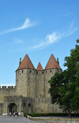Fototapeta na wymiar Cité médiévale de Carcassonne, la porte Narbonnaise sous un ciel bleu orné de fins filaments de nuages blancs.