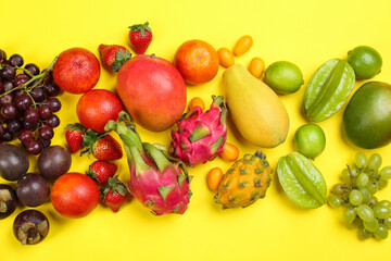 Assortment of fresh exotic fruits on yellow background, flat lay