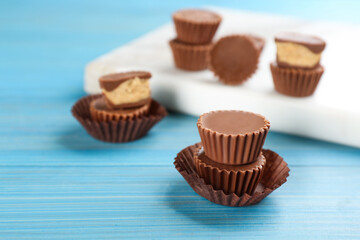 Delicious peanut butter cups on light blue wooden table, space for text